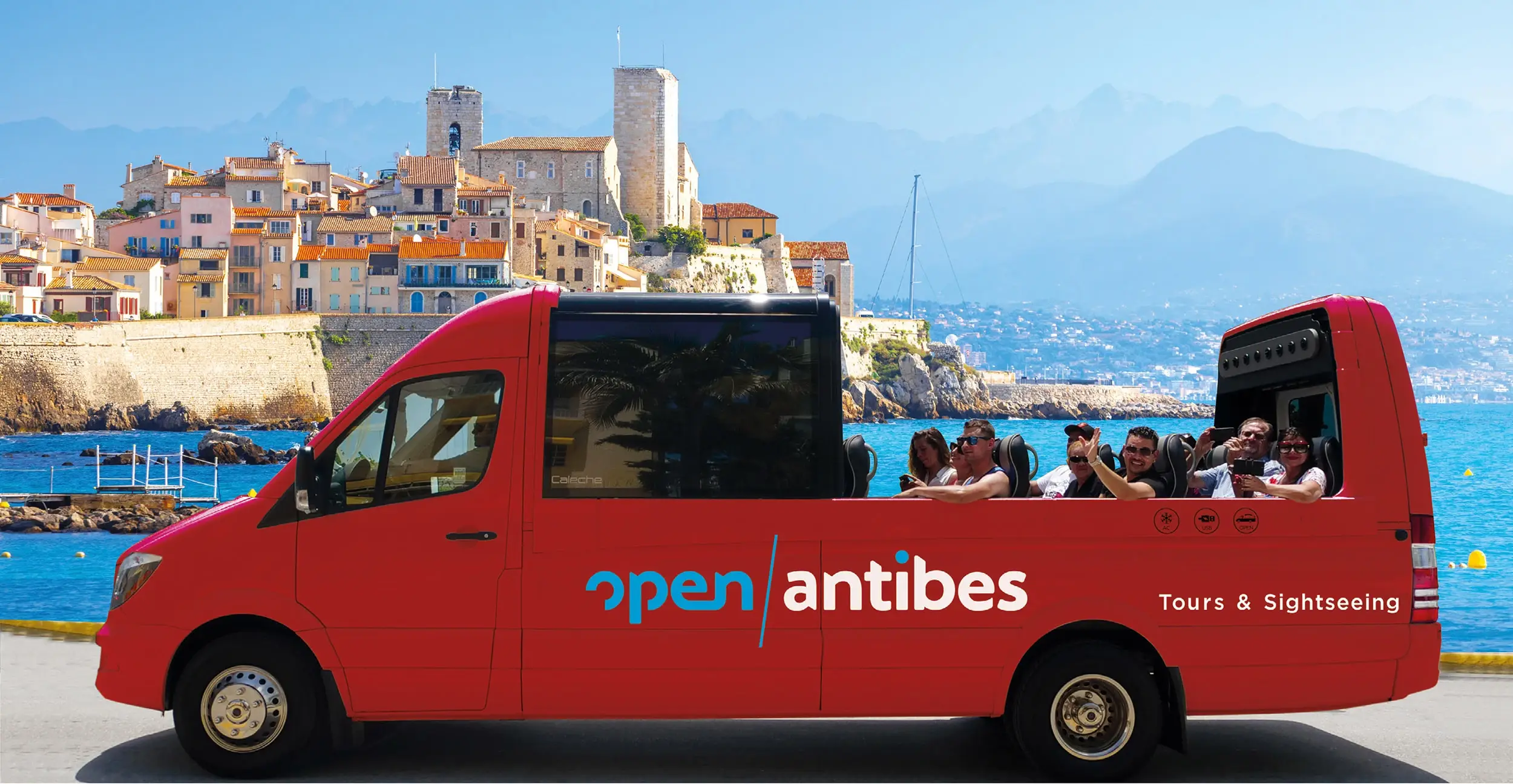 The red Open Antibes convertible bus and its passengers in front of old Antibes