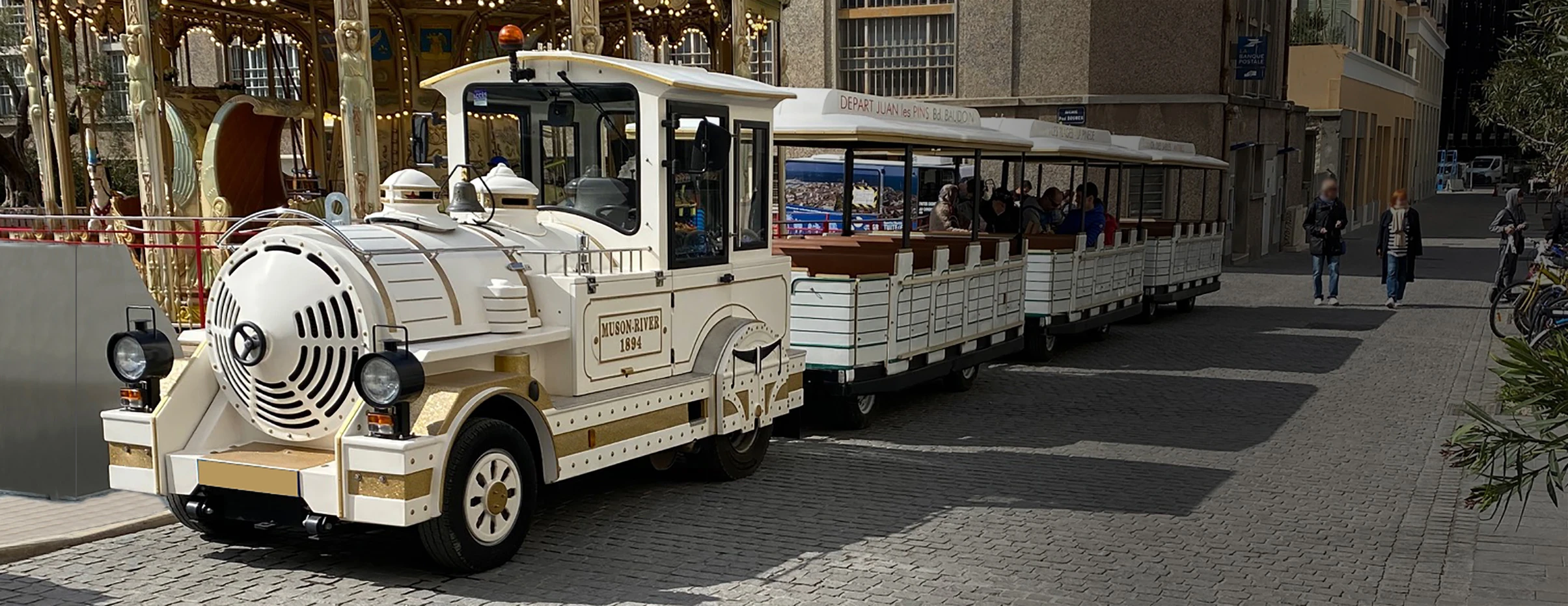 The white Petit Train and its carriages in front of the Antibes carousel